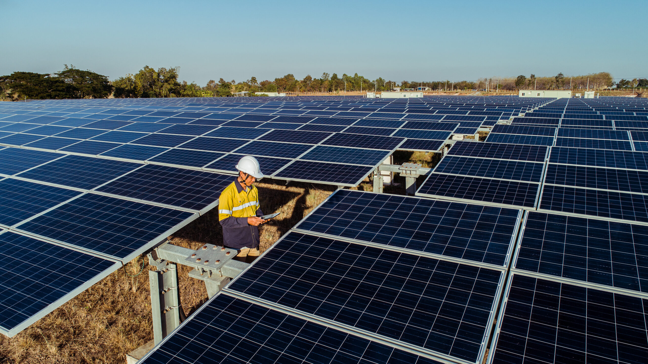 Technician and investor walking in Solar cell Farm through field of solar panels checking the panels at solar energy installation.Solar cells will be an important renewable energy of the future.