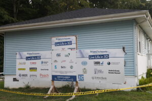 The sponsors of the 3D printed home construction that was being performed are on a blue structure on the worksite site.