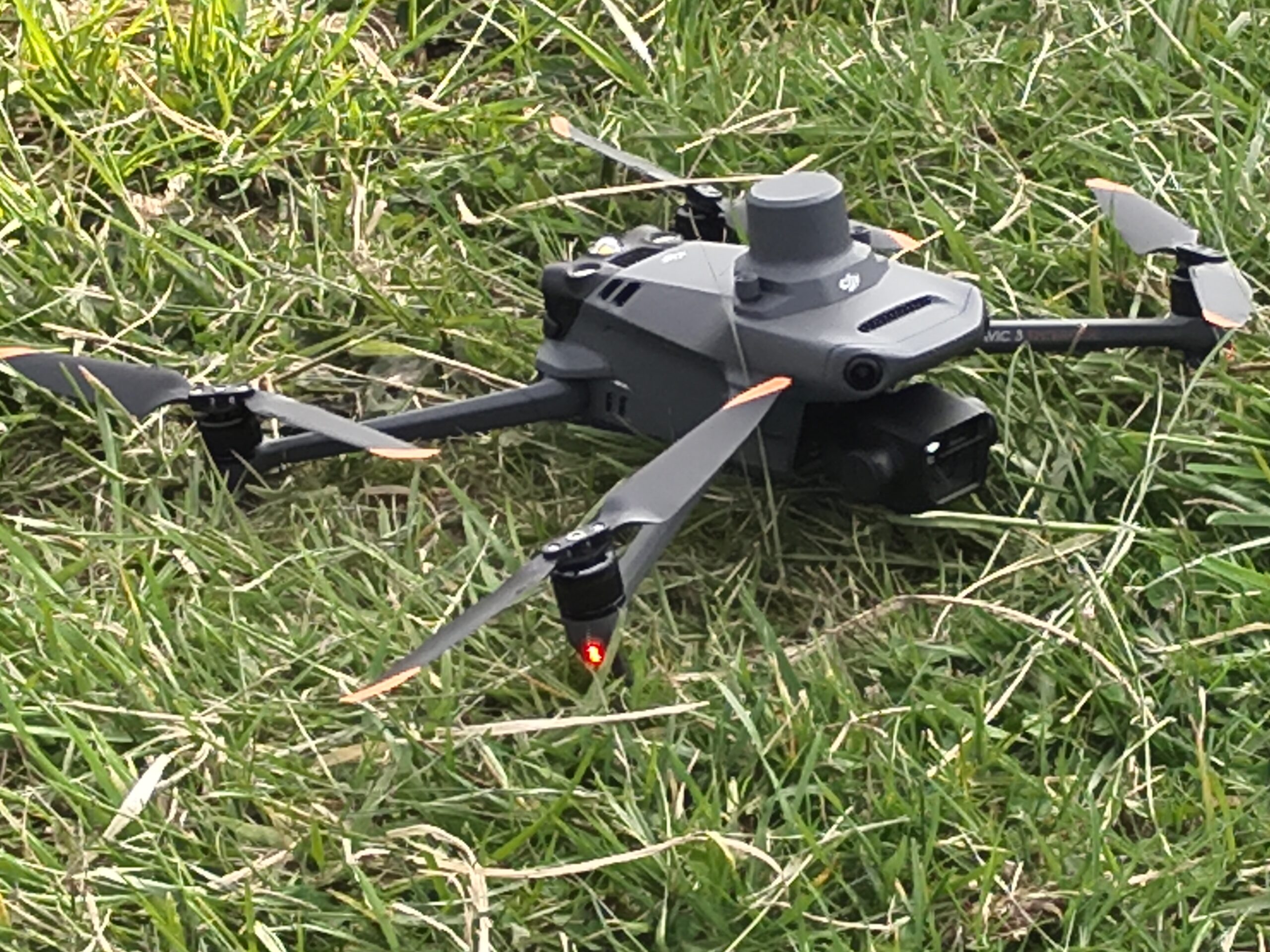 Photo of a black and dark grey drone sitting on grass.