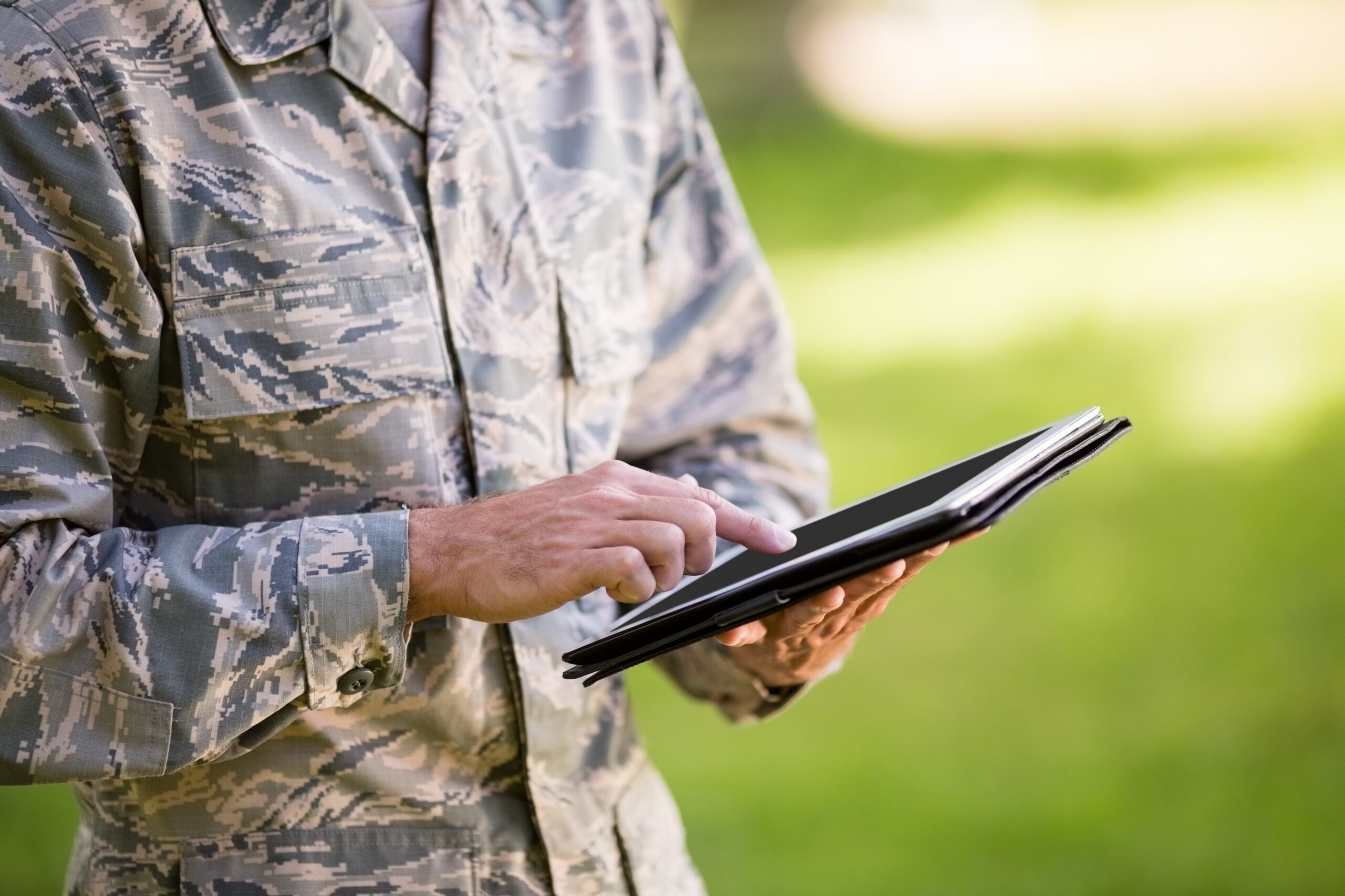 Mid section of soldier using digital tablet in park