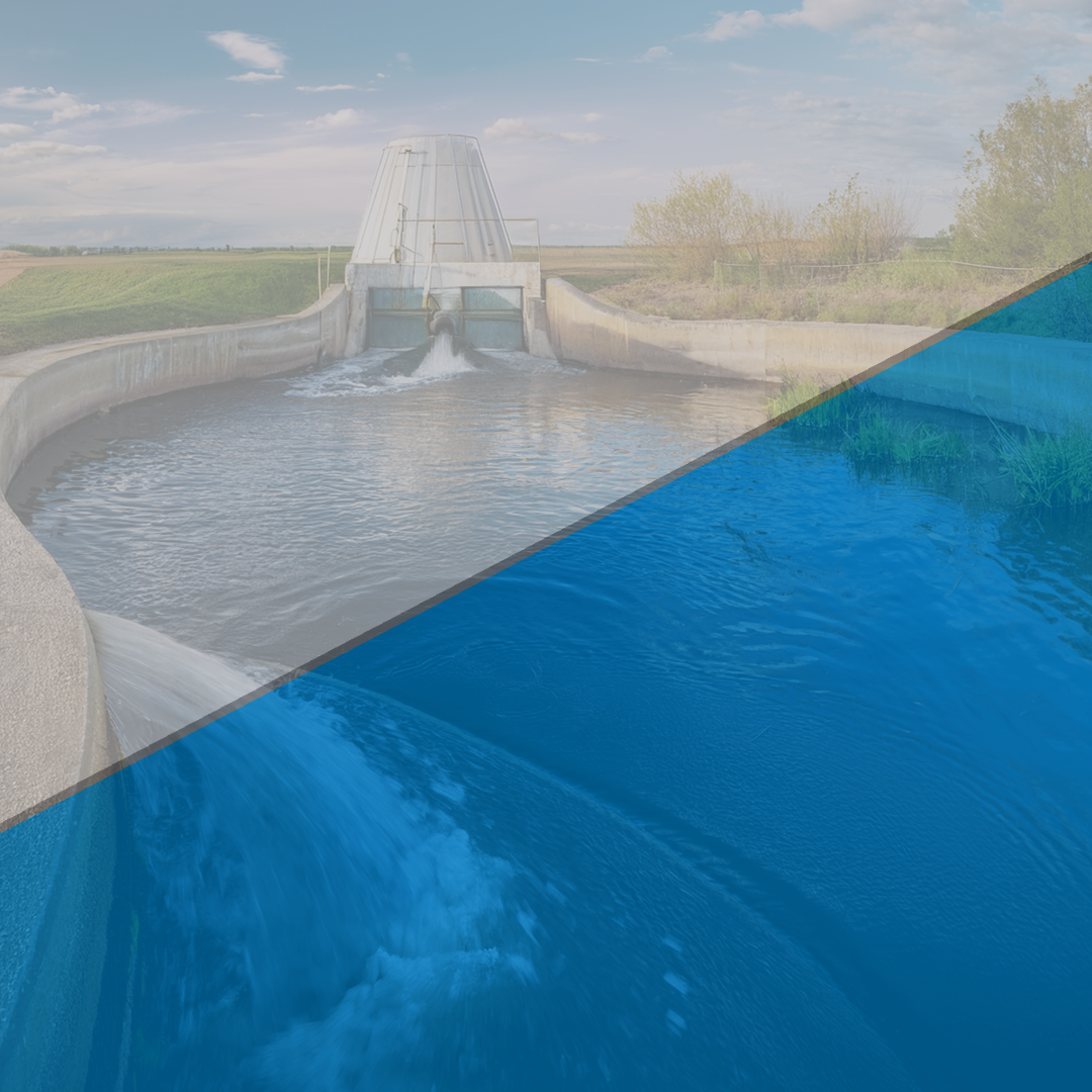 A water management facility with a concrete channel releasing water into a reservoir. A metal structure with pipes controls the water flow, surrounded by grassy fields and trees in the background. A blue overlay partially covers the lower portion of the image.