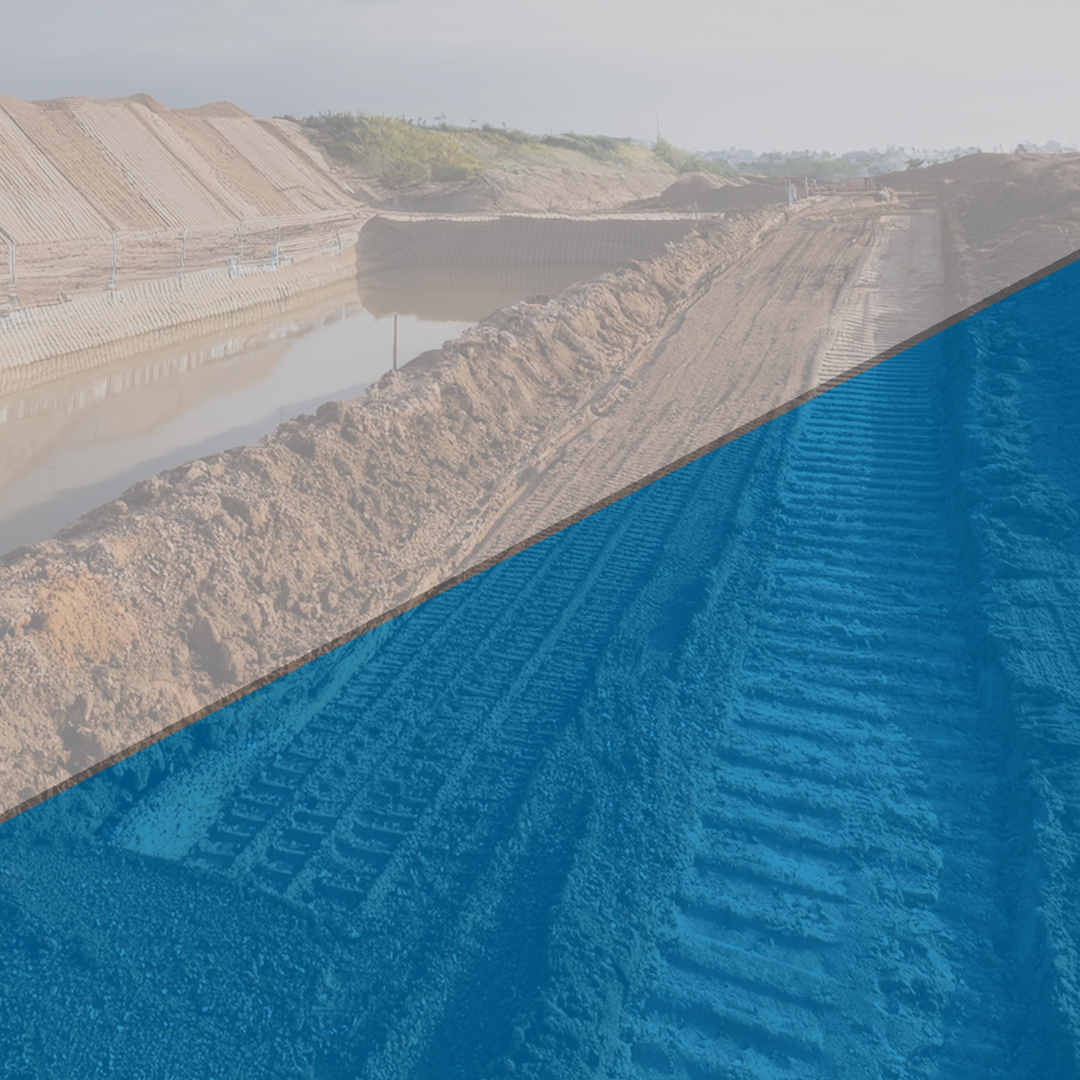 A large-scale construction project with an excavated trench filled with water, surrounded by dirt embankments. A blue overlay covers part of the image.