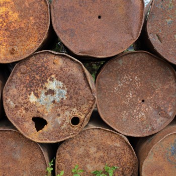 Old, rusty metal fuel tanks stacked in a row, representing decommissioned underground or above ground storage tanks addressed during environmental remediation efforts.
